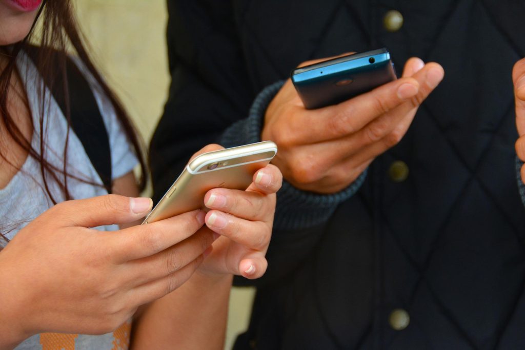 Estudante online - Foto de dois adolescentes mexendo no celular