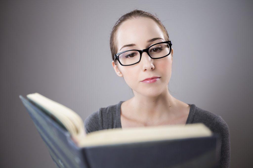 Mulher de óculos lendo uma agenda escolar. A imagem ilustra post sobre erros na comunicação da escola.